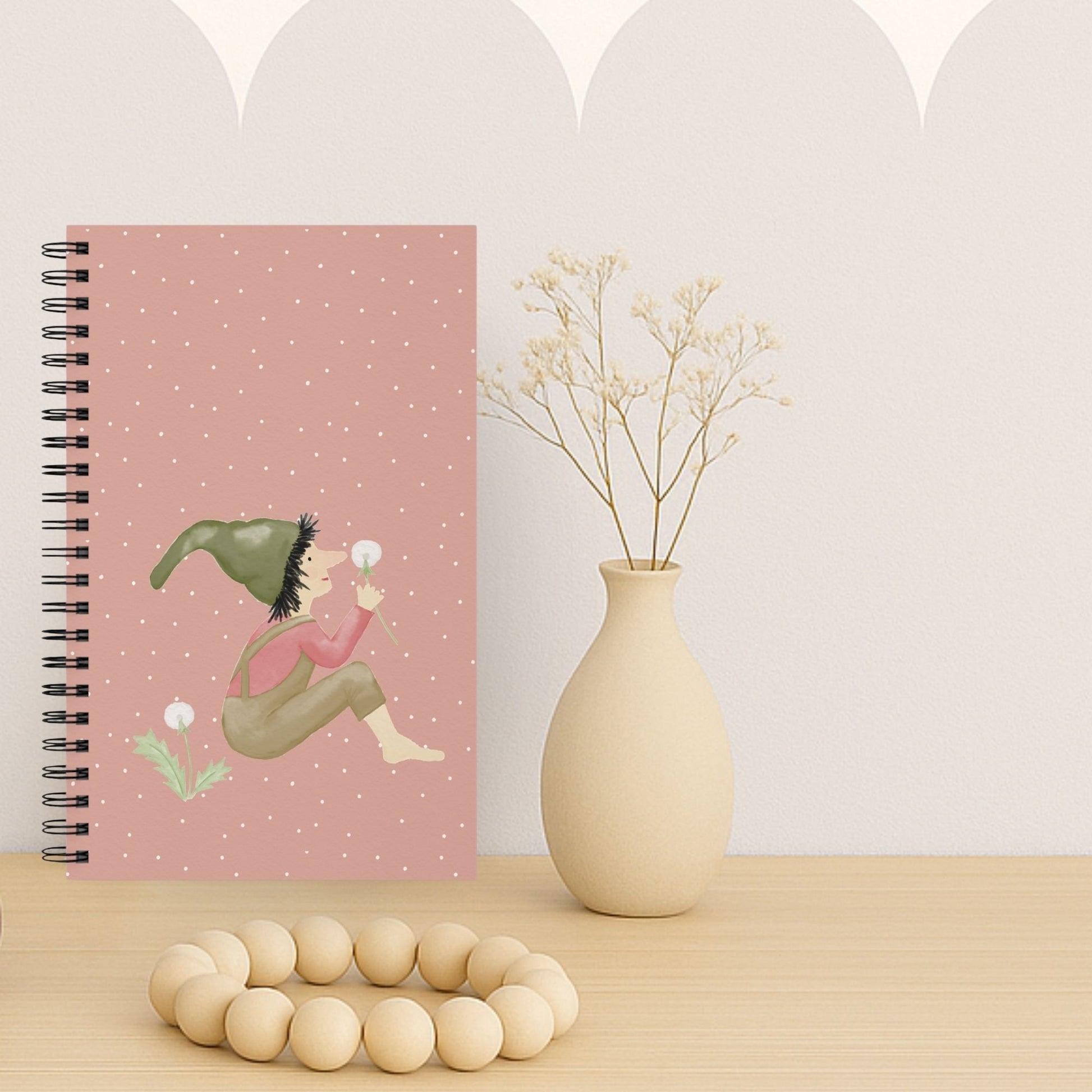Notizbuch mit Zwergenmotiv und Pusteblume auf hellem Schreibtisch